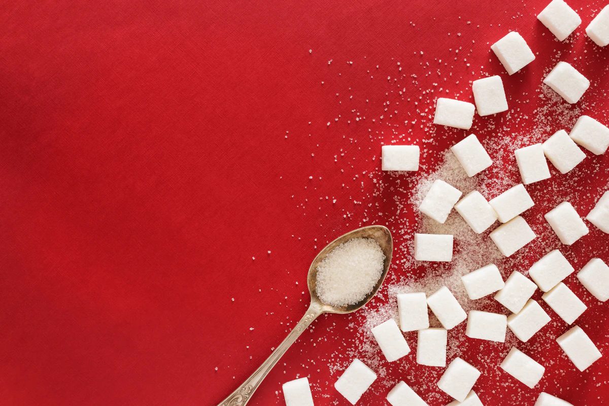 Sugar cubes and a spoon on a red surface
