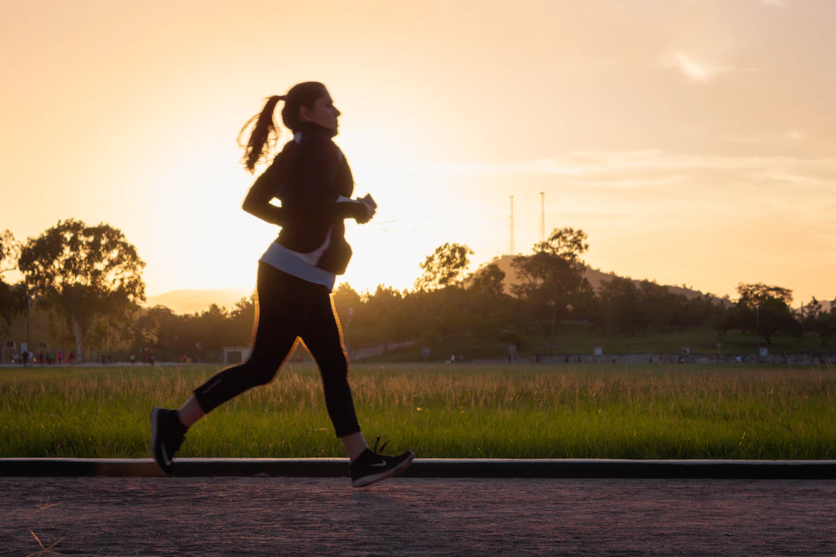 A woman in silhouette running on a path during the golden hour