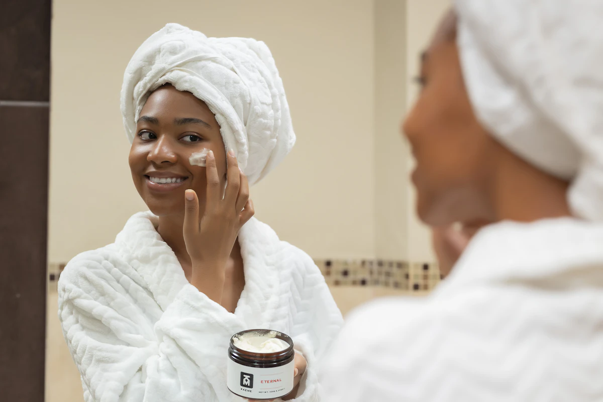 A woman with a towel on her head applying face cream