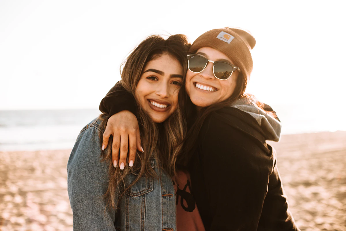 Woman hugging another woman while smiling at the beach