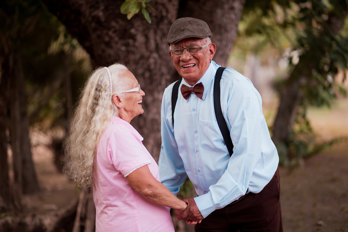 Older man and woman laughing together near a tree