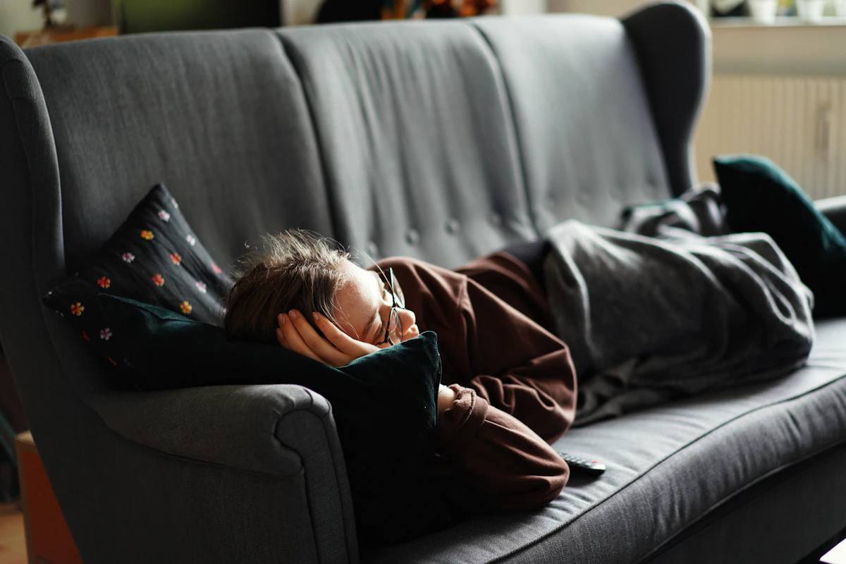 Woman in a pink jacket lying on a gray couch