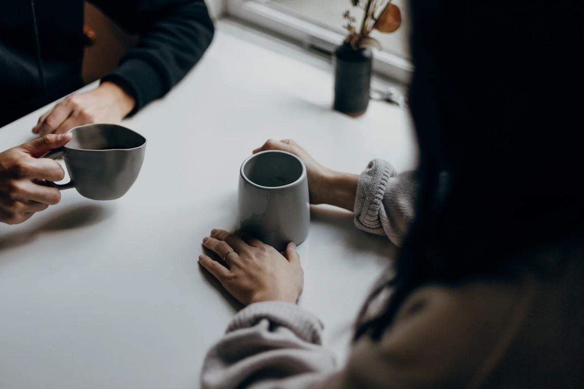 Two people holding gray mugs at a table