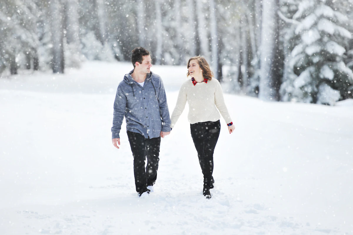 Couple walking in the snow near trees