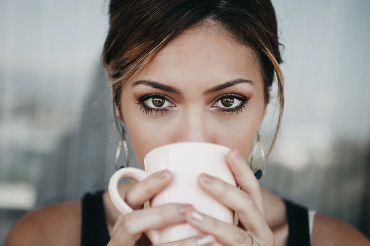 Woman drinking from a white coffee cup
