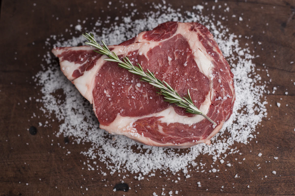 Raw steak with herbs on a wooden table