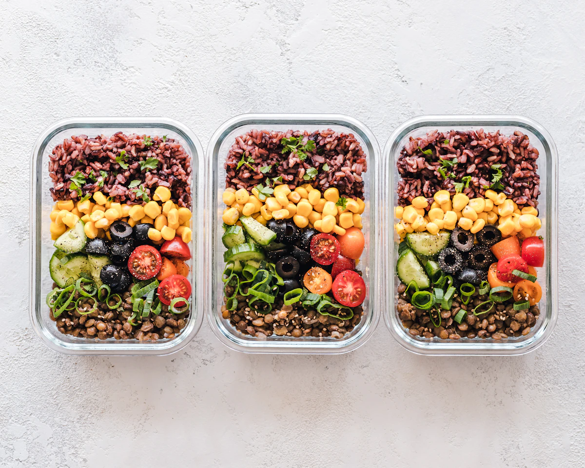 Three meal prep containers with grains and vegetables