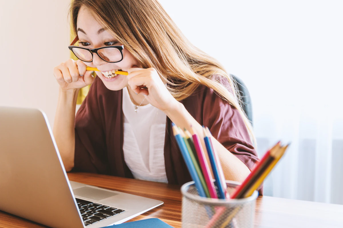 Woman biting a pencil in front of her laptop