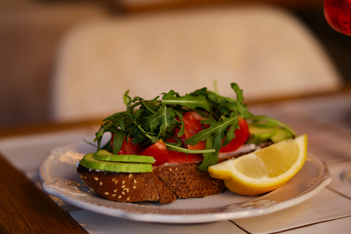 A vocado toast with tomato and a slice of lemon