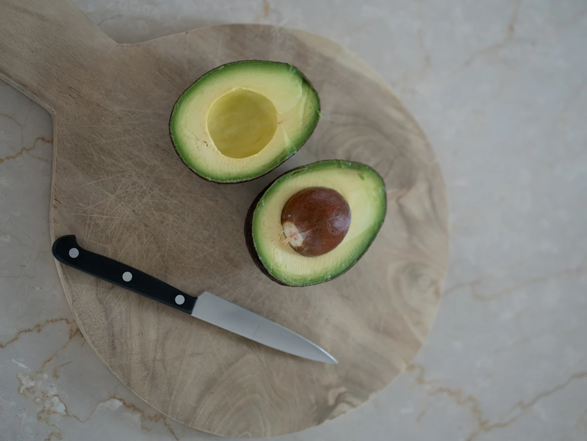 A n avocado cut in half with a knife