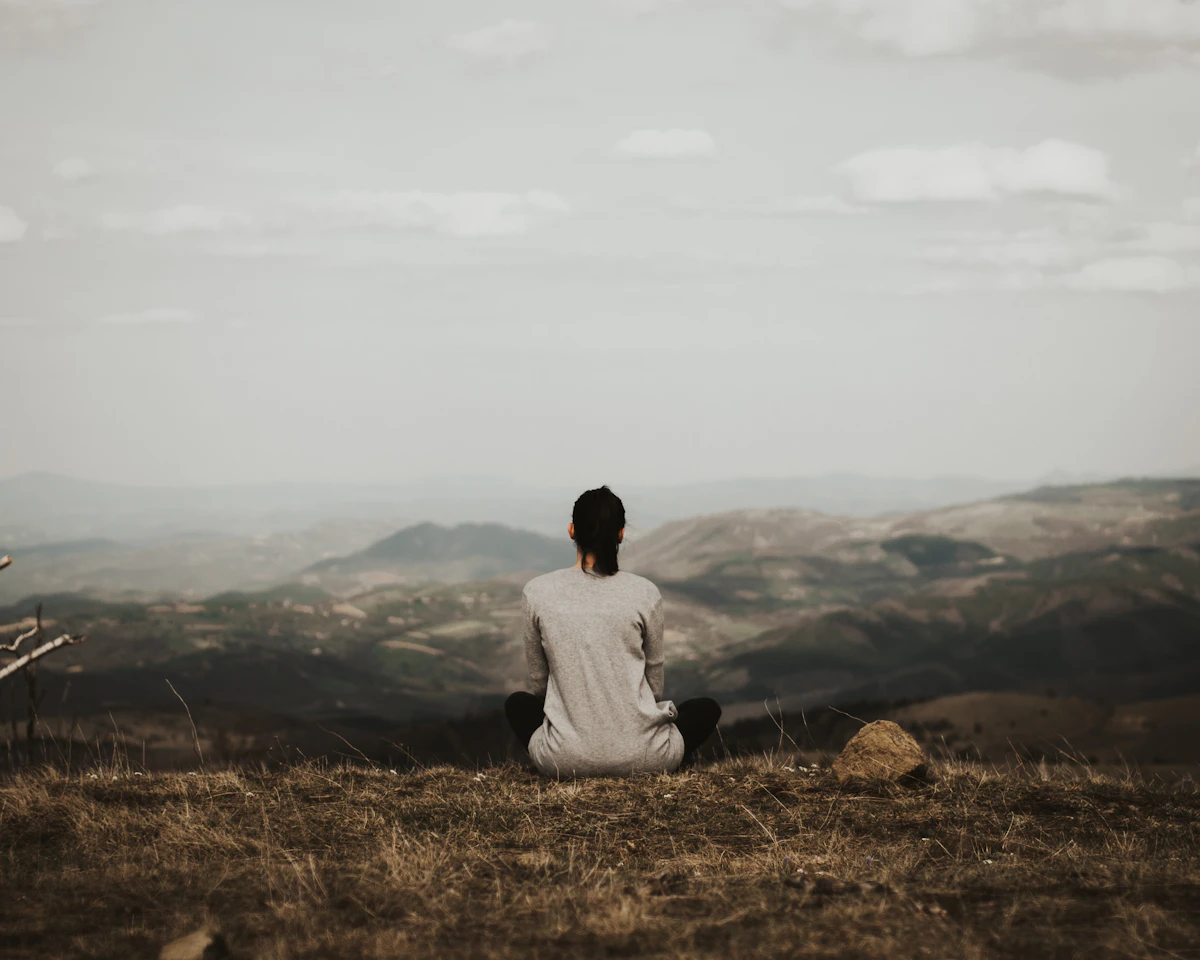 Person sitting on a hillside overlooking the mountains
