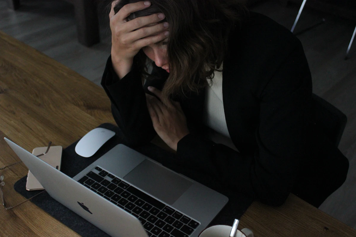 Stressed woman with her head in her hands at a laptop