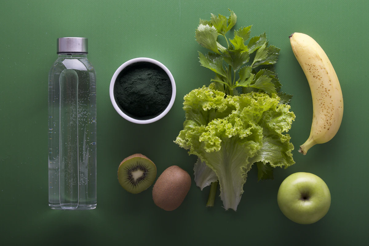 Fruits, vegetables and a bottle of water on a green surface