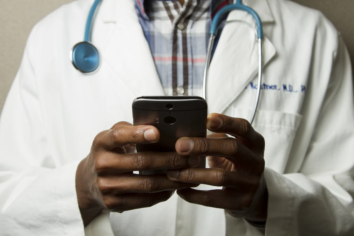 Doctor in scrubs with a stethoscope using a phone