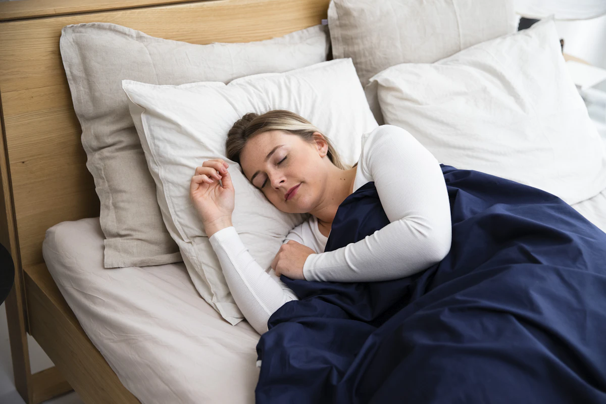 A woman sleeping on a bed with a blue blanket