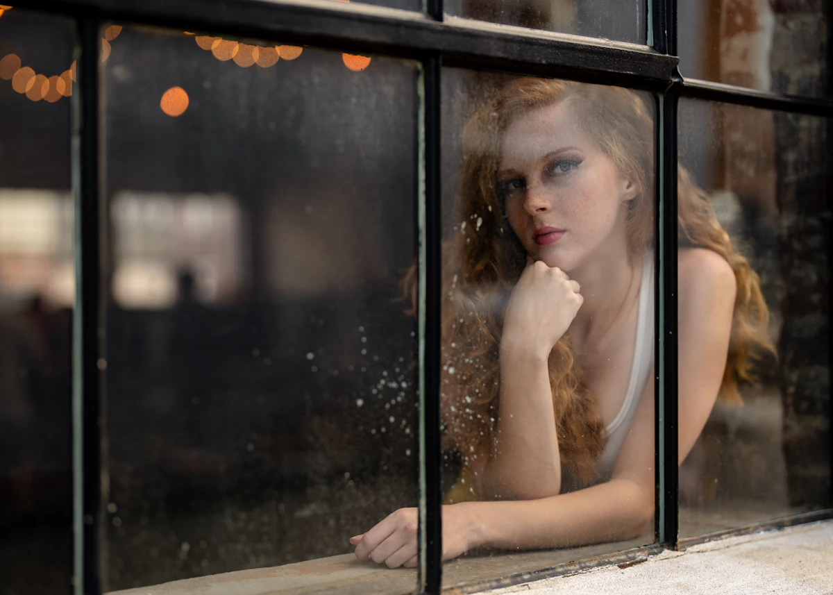 Woman looking out a rainy window, deep in thought